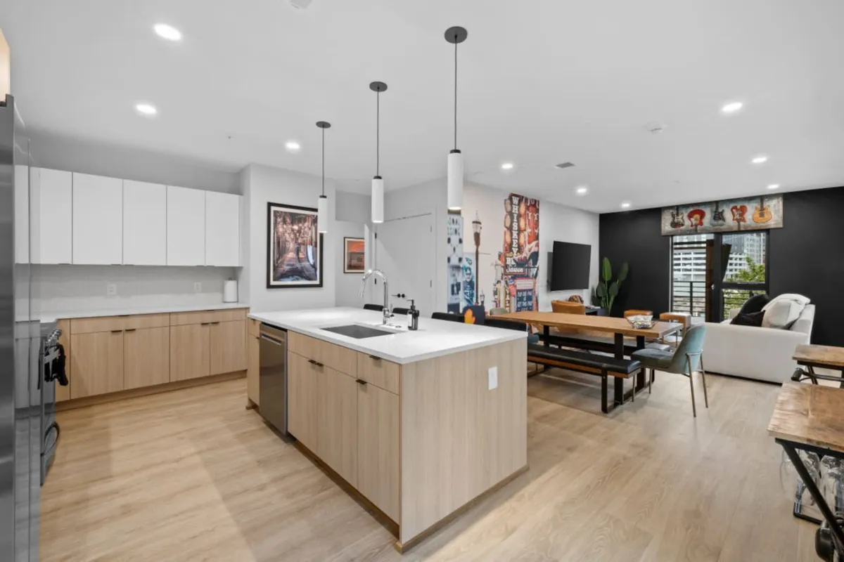 This image features a kitchen island, a dining table, wall art, and a cozy seating area. The layout encourages socializing, dining, and relaxing in a stylish, contemporary setting, seamlessly blending the breakfast bar and dining nook.