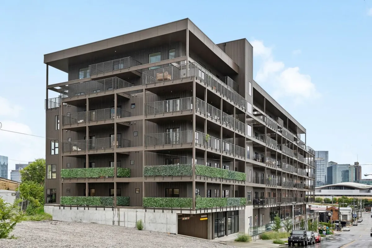 A contemporary exterior shot showcasing modern architecture, balconies adorned with greenery, and open communal spaces. The scene conveys a lively, inviting, and vibrant atmosphere, suggesting a dynamic community setting ideal for urban adventures.
