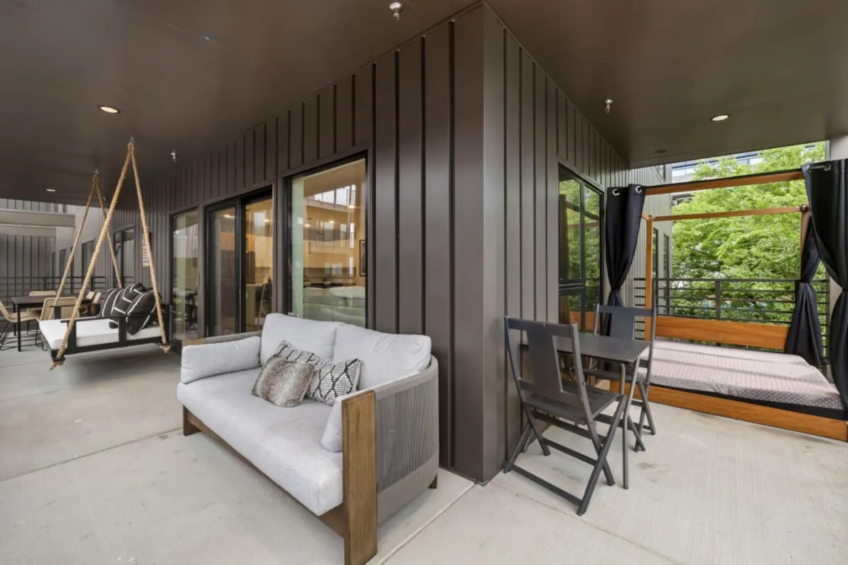 A welcoming outdoor space featuring a swing chair, cozy sofa, dining table, and daybed, set against the backdrop of a sunset sky. The layout invites small groups to relax, dine, and enjoy nature together—day or night.