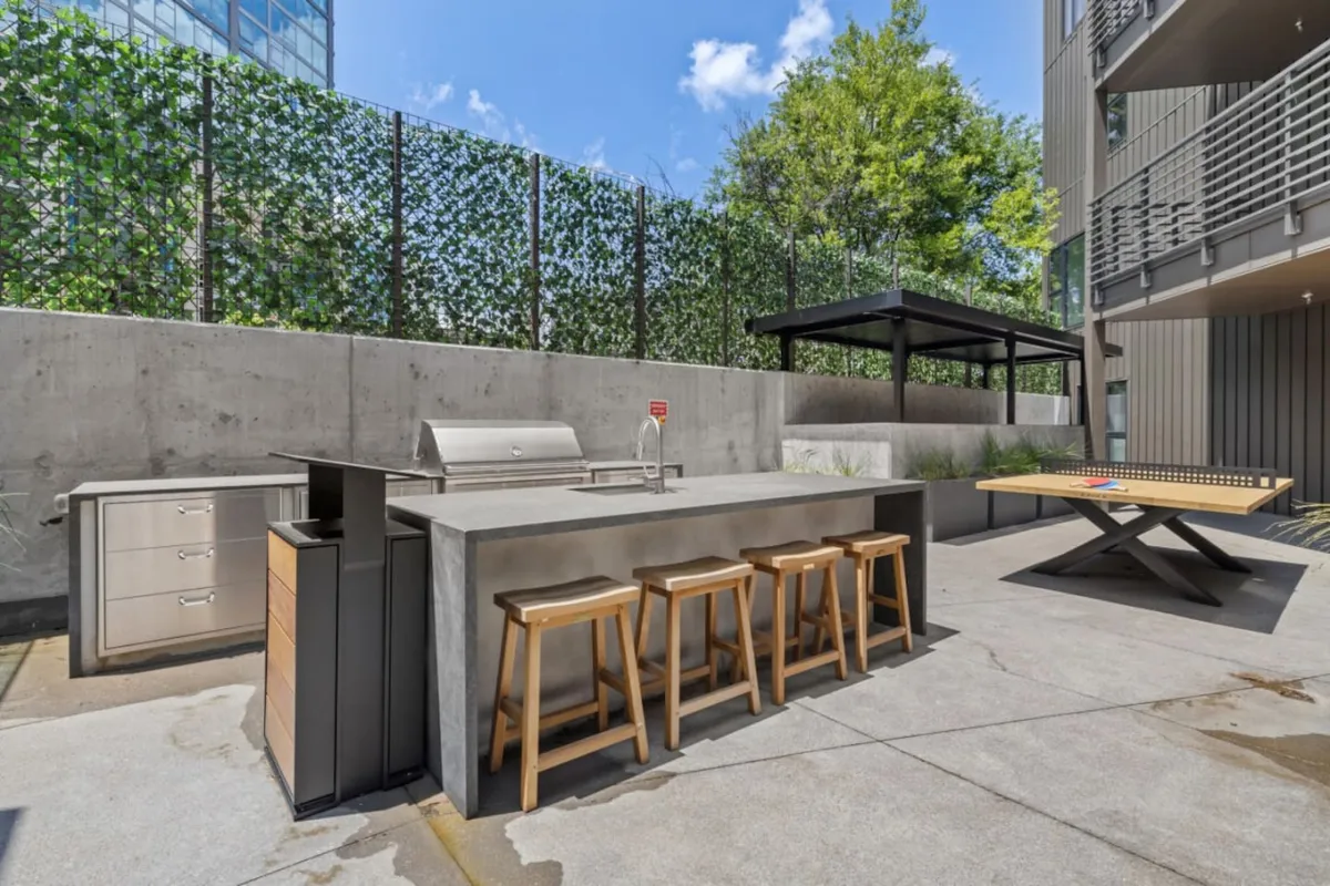An outdoor kitchen and barbecue grill area is surrounded by a modern seating and dining setup, perfect for hosting al fresco meals and lively social gatherings. The scene is bathed in natural light, encapsulating the joy of outdoor entertaining and shared celebrations.