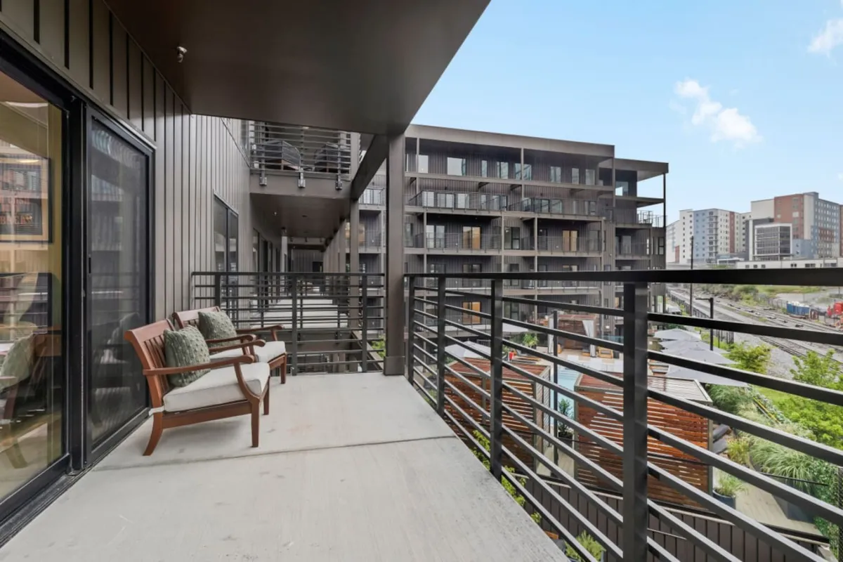 An inviting balcony with comfortable seating, modern railings, and a sweeping view of Nashville’s urban landscape. The city skyline is visible beyond the balcony, making this space perfect for relaxing outdoors while staying connected to downtown energy.