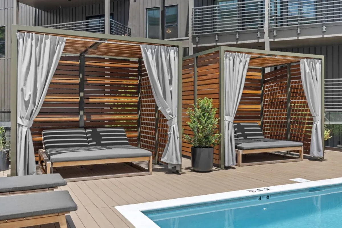 A sleek swimming pool is flanked by contemporary cabanas and stylish planters, creating a tranquil sanctuary for both sunbathing and casual poolside gatherings. The cabanas offer private, shaded spaces for relaxation, while the pool is the hub of activity and leisure.