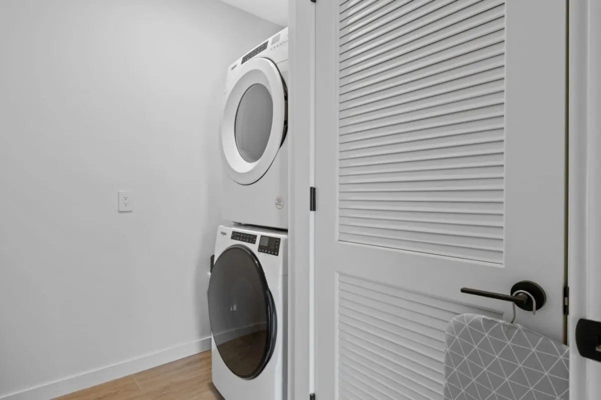 This practical interior image showcases an in-unit stacked washer and dryer against a neutral backdrop. The setup signals convenience and independence, essential for extended stays or busy professionals who value seamless routines and peace of mind during work travel.